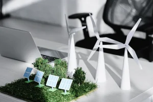 chair near table with laptop, trees, windmills, solar panels models on grass in office
