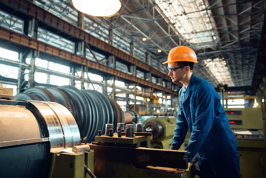 A man in a hard hat operates a machine, illustrating the importance of skilled labor in B2B engineering and manufacturing